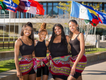 Students standing outside of Hannon Library in front of international flags after a Global Citizen Day performance.