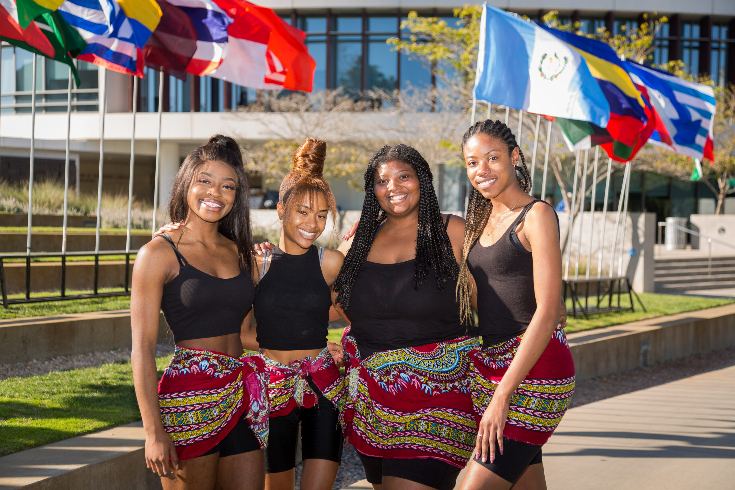 Students standing outside of Hannon Library in front of international flags after a Global Citizen Day performance.