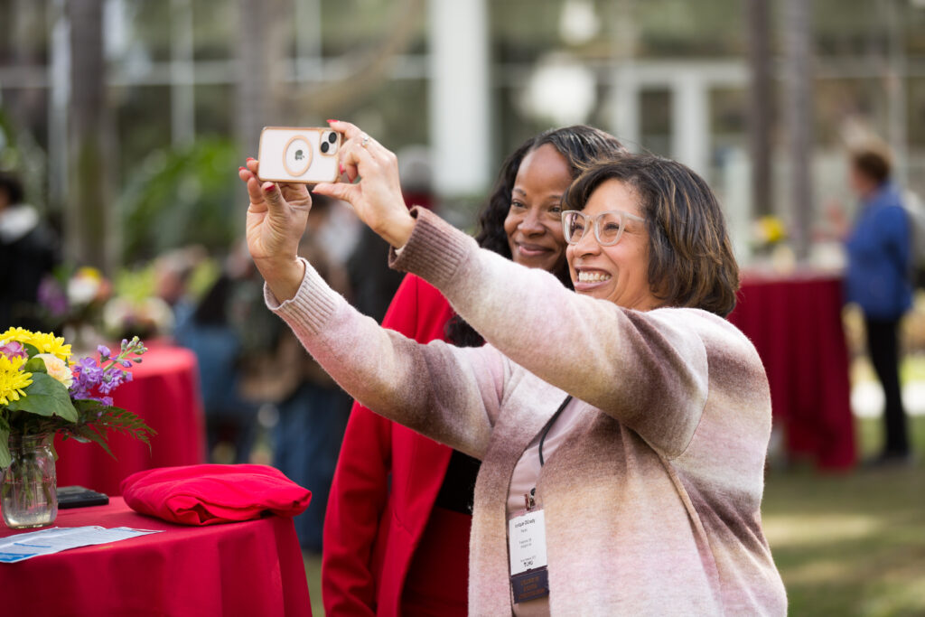 A family member and Kawanna Leggett pose for a selfie photo outside during a reception.