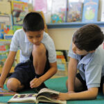 Two elementary children reading a book together in a classroom
