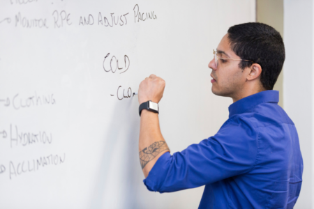 Prof. Caio Sousa writes on white board