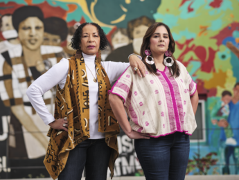 Cheryl Grills and Sandra Villanueva in front of colorful community coalition mural