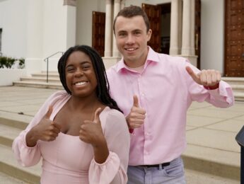 Two students in pink shirts and jeans stand on the chapel steps at LMU.