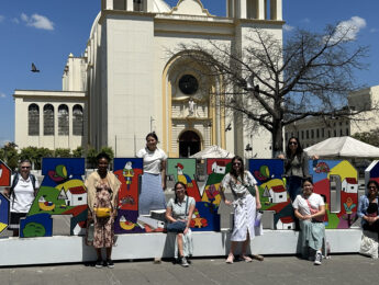 Students and staff stand on multi-colored letters outside in El Salvador.