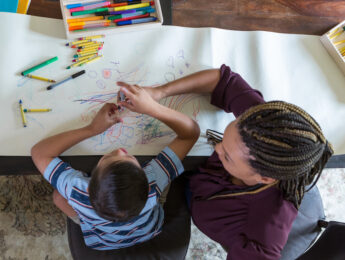boy coloring with female therapist during play therapy session.