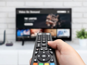 Man watching TV, remote control in hand. VOD service on TV