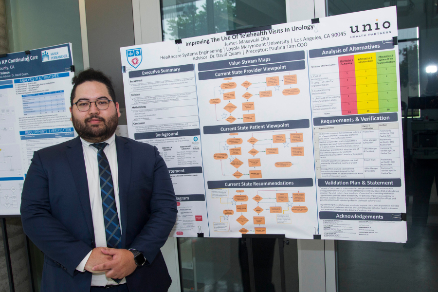 Student stands next to the poster board for his project titled '“Improving the Use of Telehealth Visits in Urology'