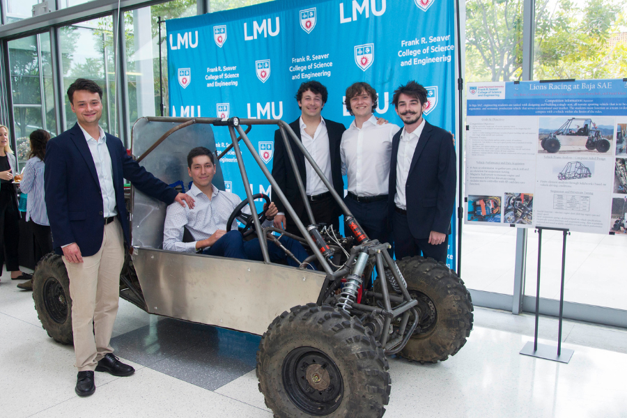 Five students smile next to their capstone project, a Baja race car