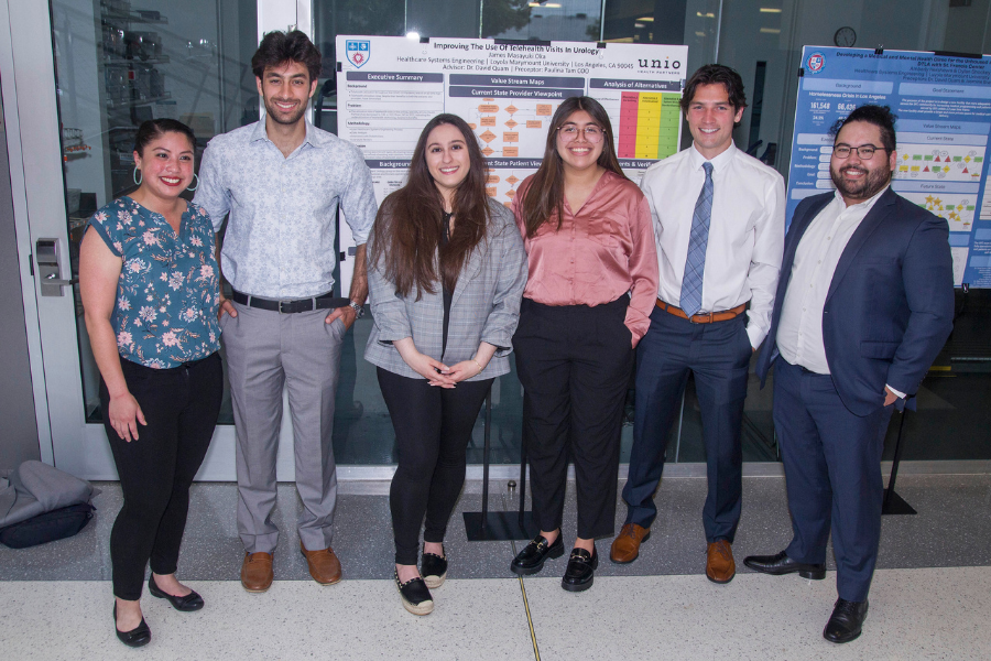 Six students stand by their Engineering Design Showcase projects