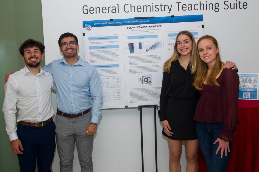 Four students stand smiling next to the poster board for their project titled 'Solar Water Desalination'