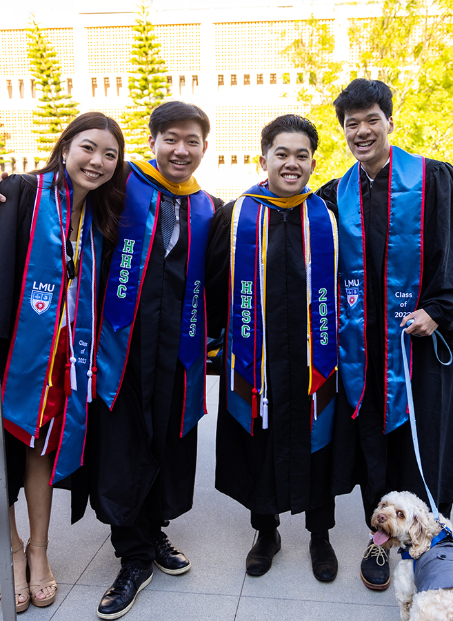Four HHSC graduates and a dog pose for a photo