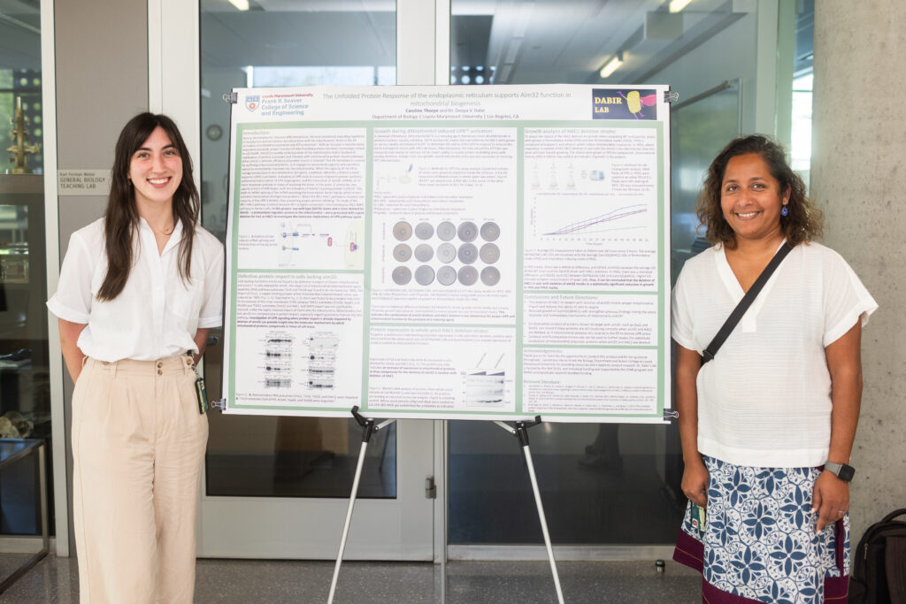 student and professor stand next to poster board