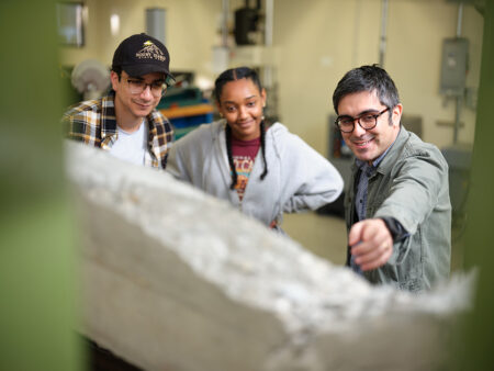 Professor and students examine the breaking point of a concrete beam.