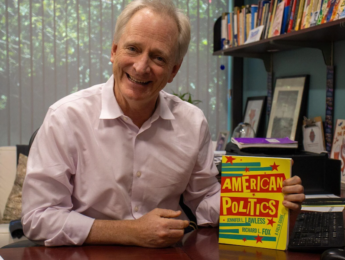 Richard Fox pictured in office with his book American Politics