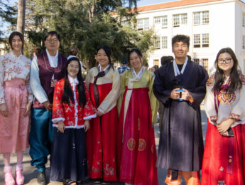 Students and staff gather outside in red, gold, and pink traditional attire for Lunar New Year.
