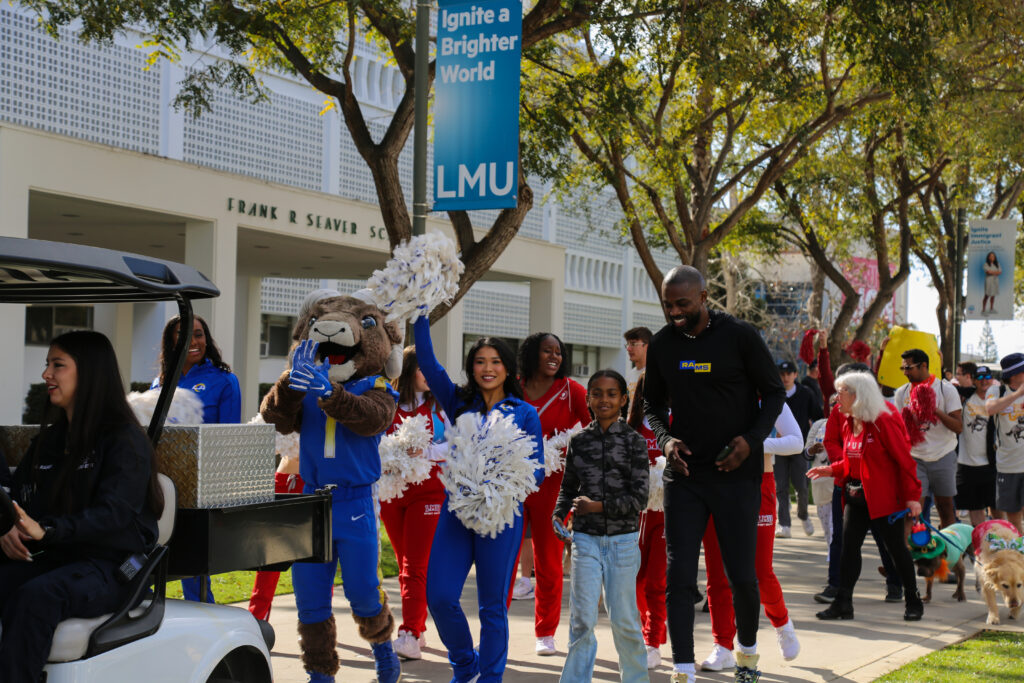 A parade full of cheerleaders, the Rams mascot, a former player dressed in black parade down Alumni Mall.