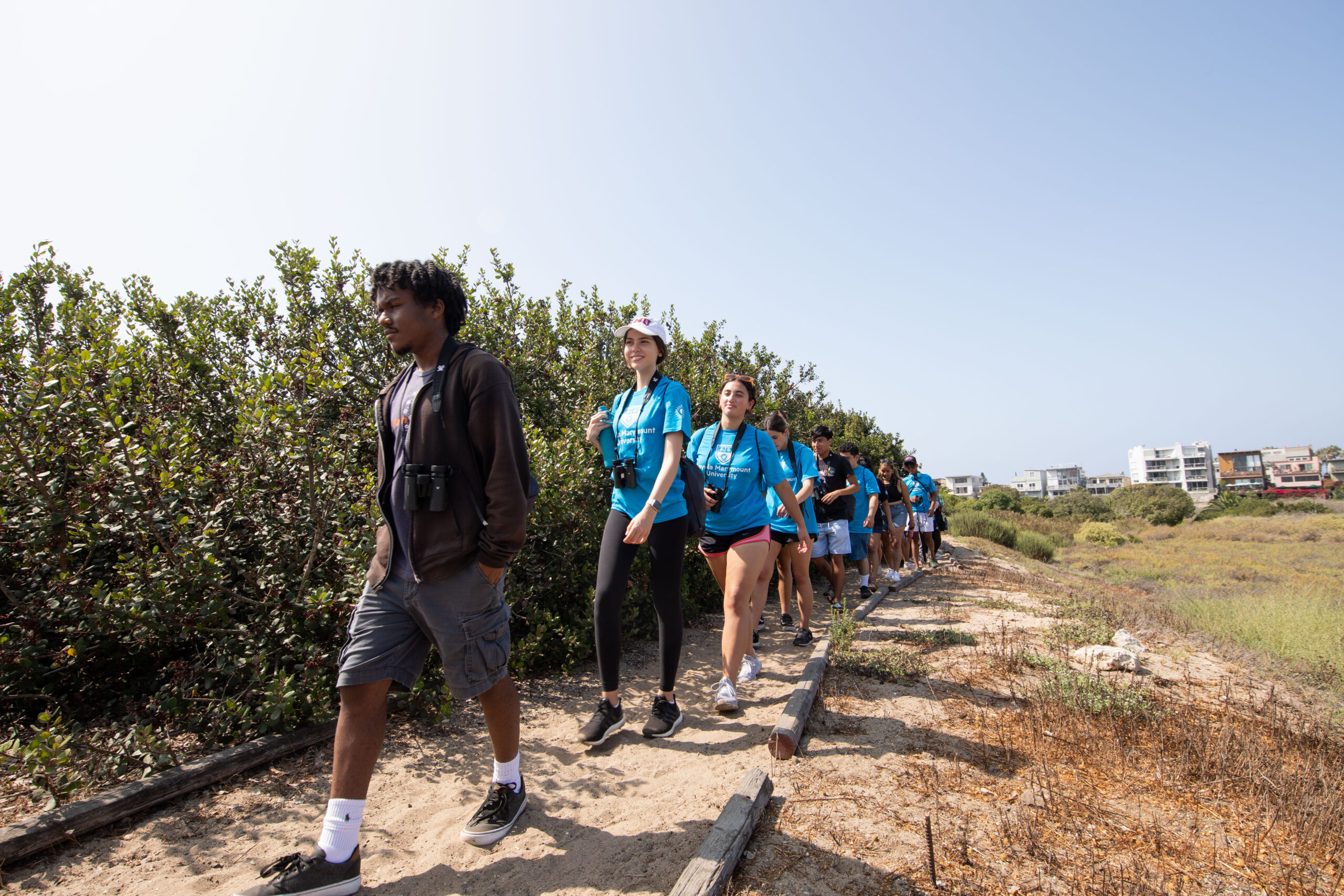 Students and a volunteer walk outside on a dirt path.