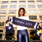 A young woman holds a pennent which reads "Angel City"