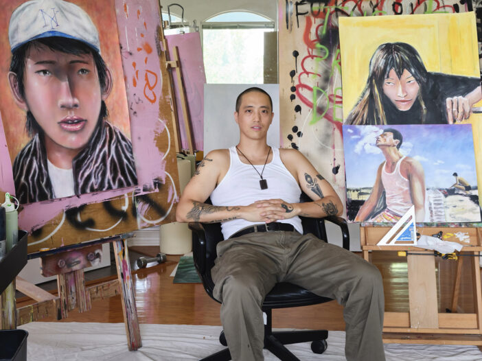 an artist sits in his studio in front of paintings