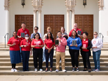 Staff pose outside in front of the chapel with awards.